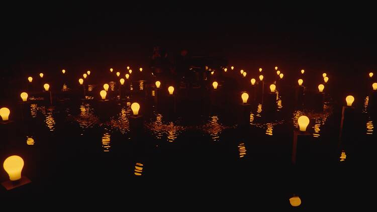 Rows of glowing bulbs over still water